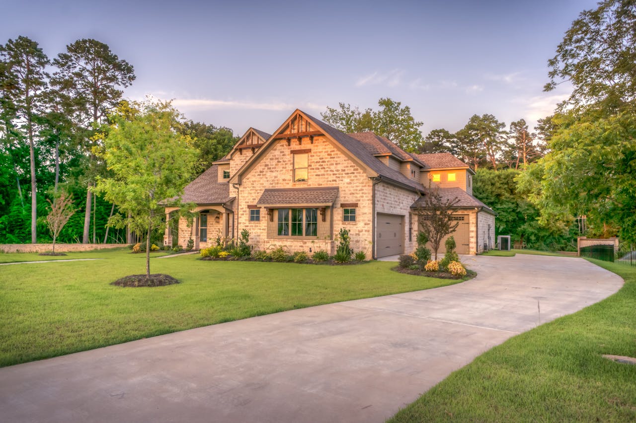 about-img Elegant stone family home surrounded by trees, lush lawn, and vibrant garden.
