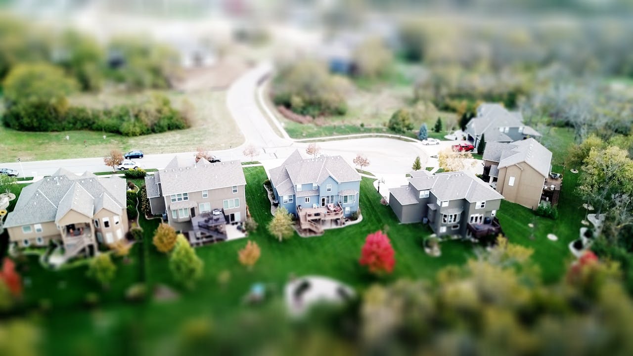 gallery-img-03 Aerial photo showcasing residential houses in a suburban neighborhood with lush greenery and streets.