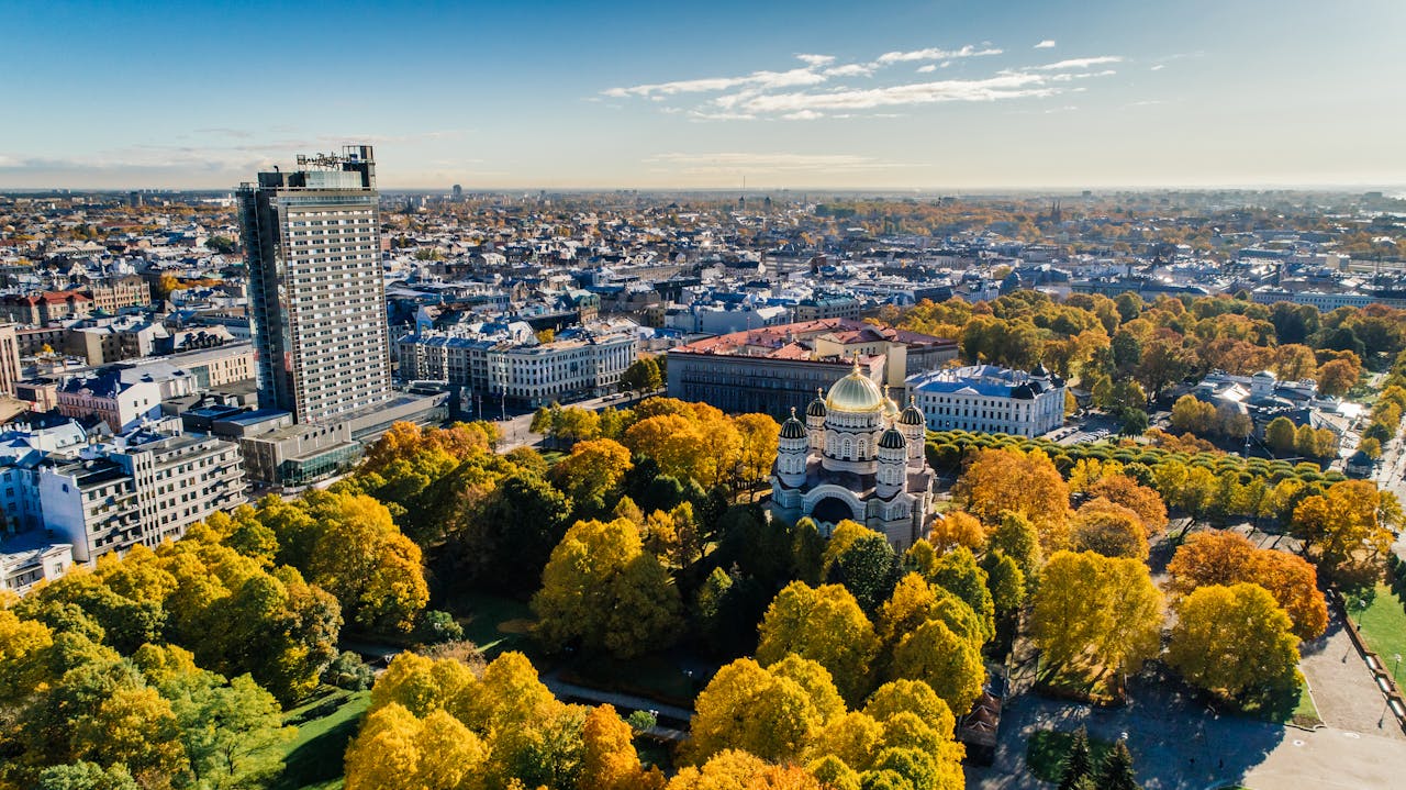 A stunning aerial view of Riga showcasing a cathedral, city architecture, and vibrant fall foliage.